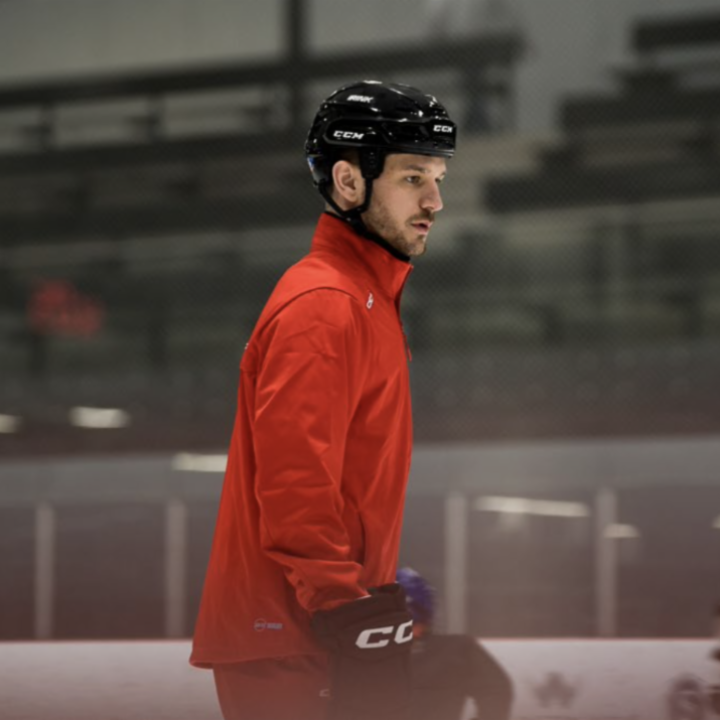 Image of Sam Jones skating on the ice and wearing a red tracksuit